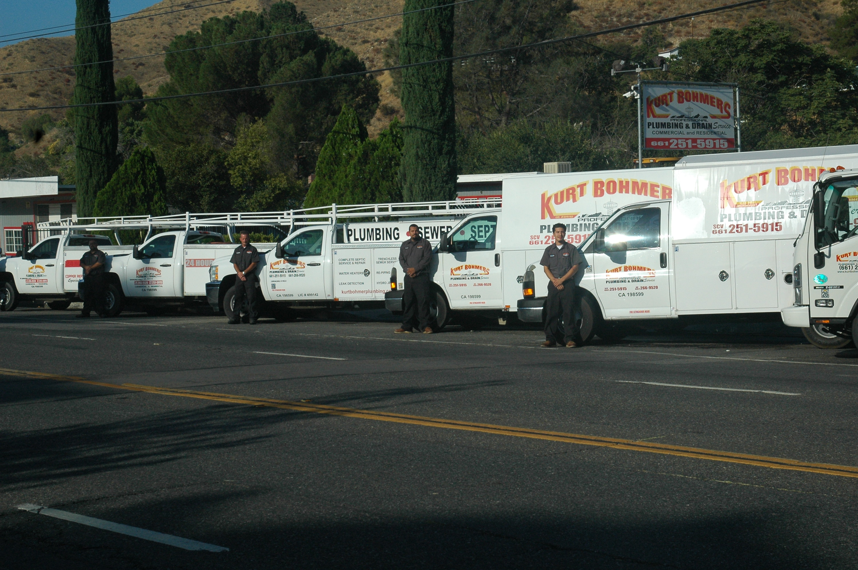 Kurt Bohmers Plumbing employees standing in front of their service trucks