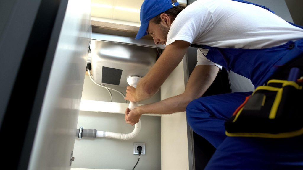 Handyman checking clogged water pipe, installing faucet plumbing, repair service
