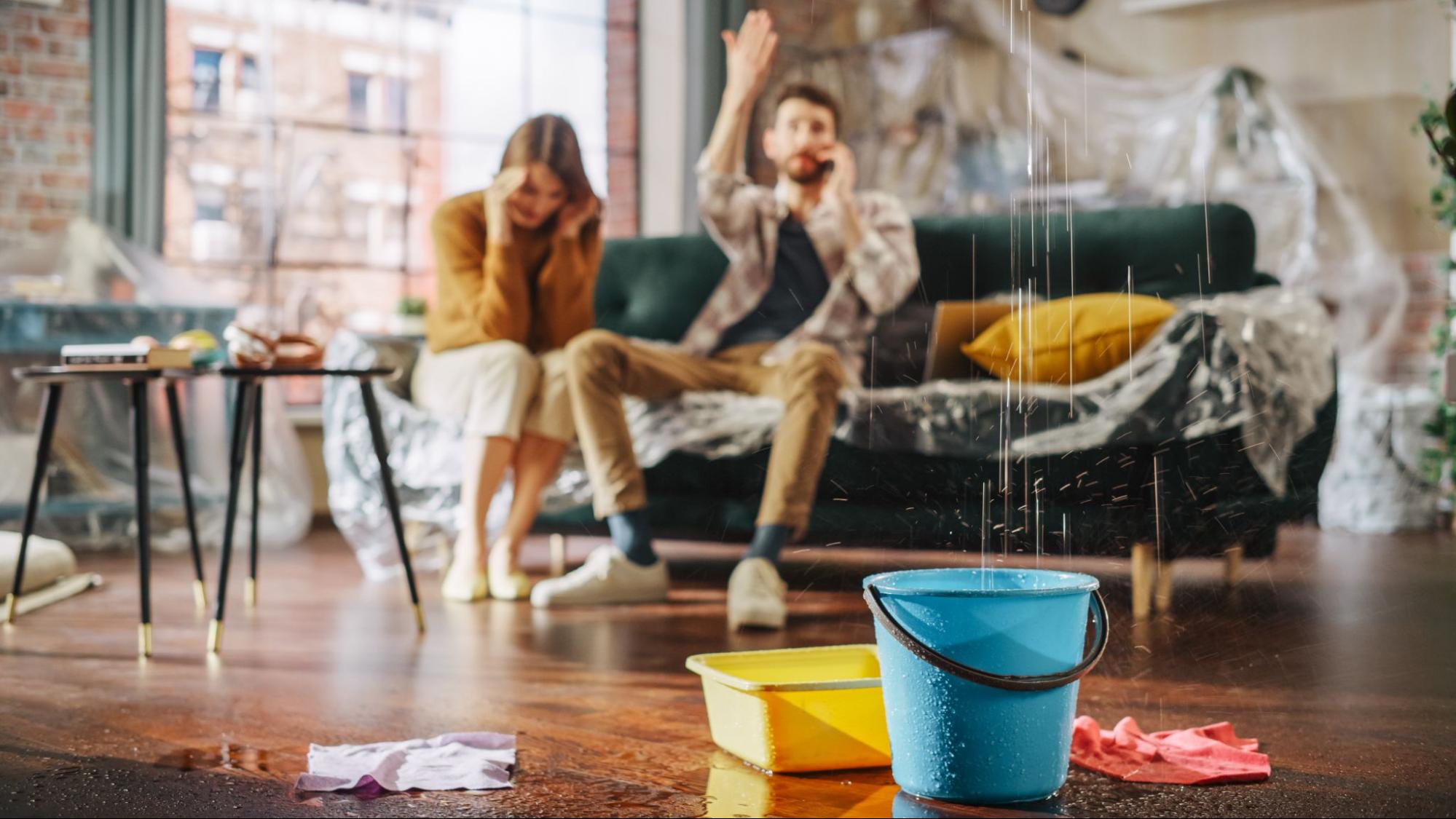 man and woman on their couch watching a plumbing leak into their home